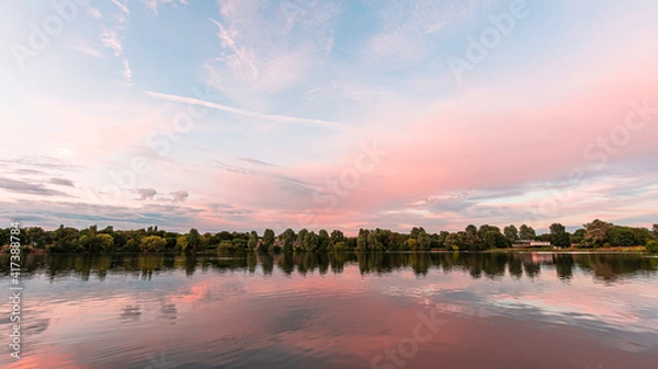 Obraz Sunset over Westport lake in Stoke on Trent, Staffordshire, UK.Reflection of blue sky and pink clouds on a calm water surface.Bright landscape scenery with pastel colours.Tranquil nature scene.