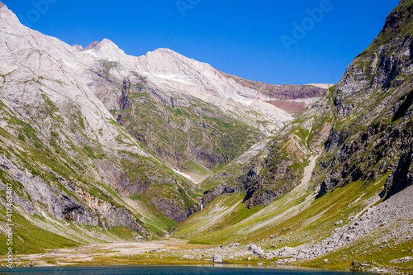 Obraz High snow-capped peaks and a glacier from a beautiful lake in a green meadow in summertime