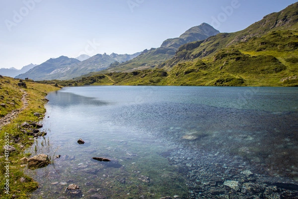Obraz Beautiful panoramic view of a lake with crystal clear water and beautiful green mountains in the background in summertime