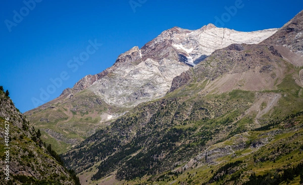 Obraz Green valley with mountains in the background under a blue sky