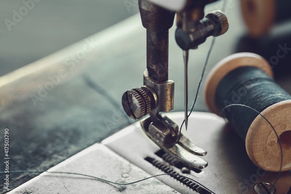 Fototapeta Close up of sewing needle. Spool of thread on working part of antique sewing machine.