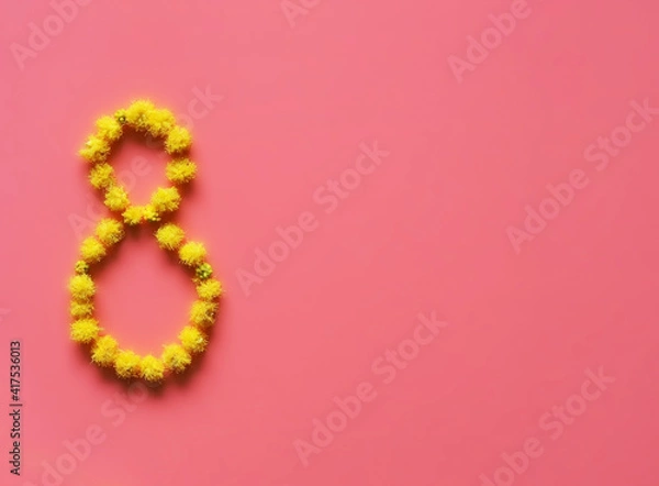 Fototapeta Figure 8 is lined with yellow fluffy mimosa flowers on the pink backdrop of the International Women's Day Spring Postcard holiday free space for text