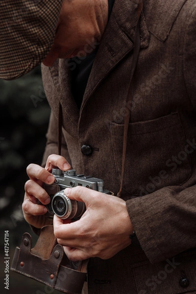 Obraz photographer with a retro camera in his hands. Dressed in retro style, jacket and cap