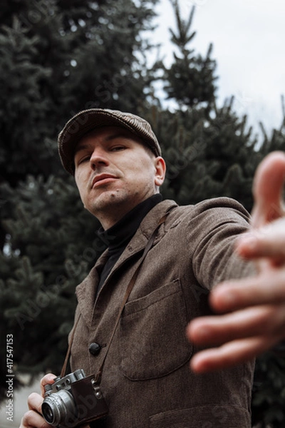 Obraz photographer with a retro camera in his hands. Dressed in retro style, jacket and cap