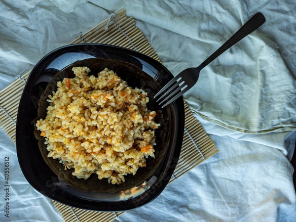 Fototapeta photo of pilaf in a black plate on a white background. rice dish. photo of food.  View from above. 