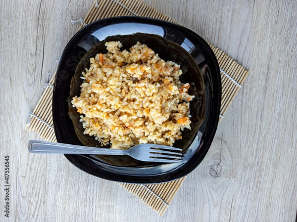Fototapeta photo of pilaf in a black plate on a white background. rice dish. photo of food.  View from above. 