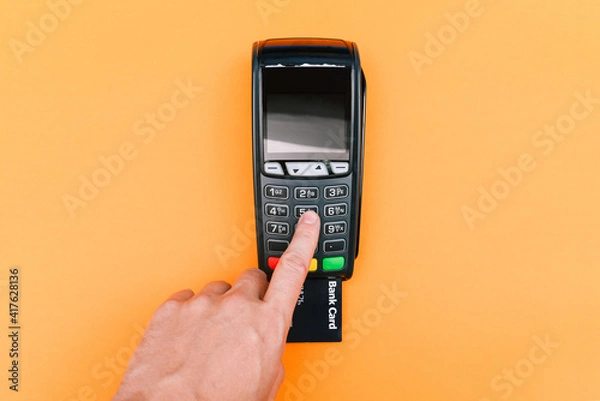 Fototapeta Man entering a password at a POS terminal. Wireless, contactless or cashless payments, RFID NFC. Payment by credit card, purchase and sale of goods and services