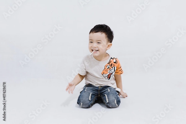 Fototapeta boy eats lollipops on white background