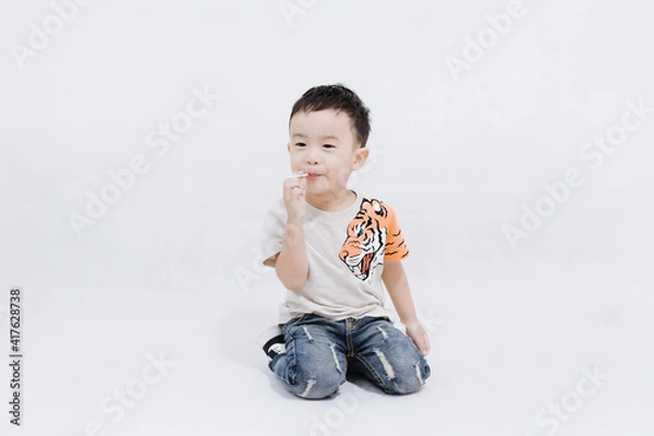 Fototapeta boy eats lollipops on white background