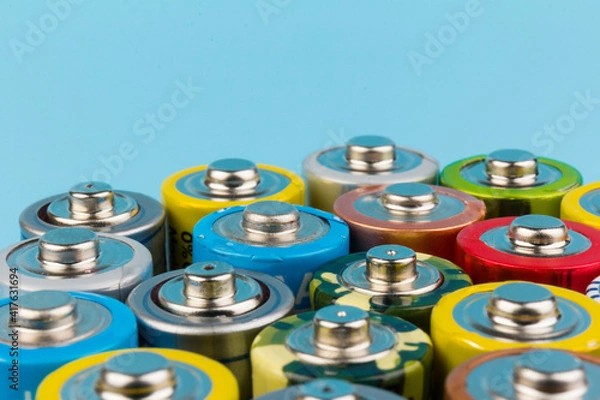 Fototapeta Photo of alkaline batteries on blue background. Recycling of rechargeable NiMH batteries. The different size of accumulators. Copy space.