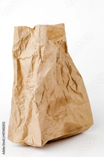Fototapeta Crumpled paper bag with greasy spots on a white isolated background. Recycling of secondary waste