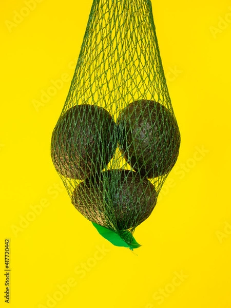 Fototapeta Avocados in a green net isolated and suspended on air
