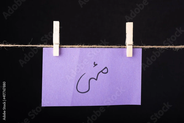 Fototapeta Translation May in urdu word written on a Purple color sticky note hanging with a wire on black background.