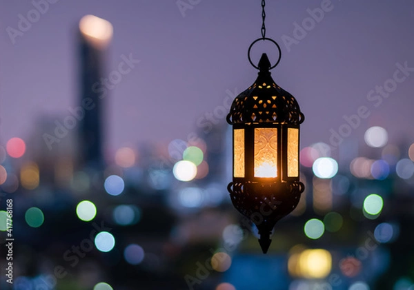 Fototapeta Hanging lantern with night sky and city bokeh light background for the Muslim feast of the holy month of Ramadan Kareem.