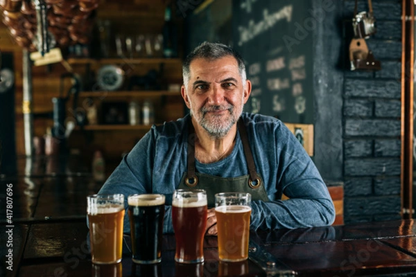 Fototapeta barman standing in bar. He is serving craft beer