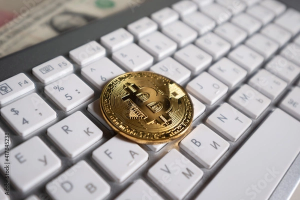 Fototapeta Bitcoin cryptocurrency coin on the background of the computer keyboard