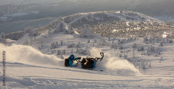 Obraz Pro snowmobiler makes a turn and lets a flurry of snow spray from under the caterpillar. sports snowmobile in the mountains. bright skidoo motorbike and suit without brands. Winter fun. panoramic view