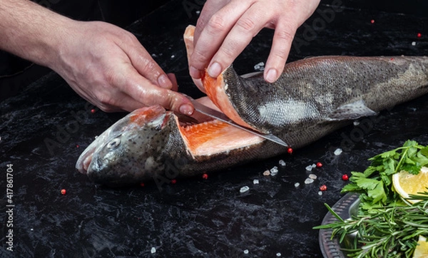 Obraz Cutting up fresh salmon on a dark table.