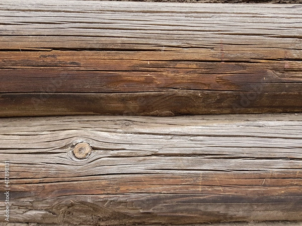 Fototapeta close-up as a background - the texture of an abandoned wooden house, a wall of old wooden blackened beams with slots, horizontally folded, connected by tow. In the countryside, outside the city. 