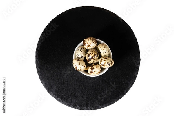 Obraz Boiled spotted quail eggs  on black stone plate , isolated on white background. Healthy Food Products Concept.