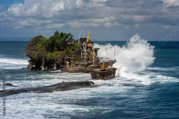 Fototapeta Tanah Lot temple Bali, Indonesia with ceremony decoration in high tide time. big wave smash the temple cliff when the tide is high.