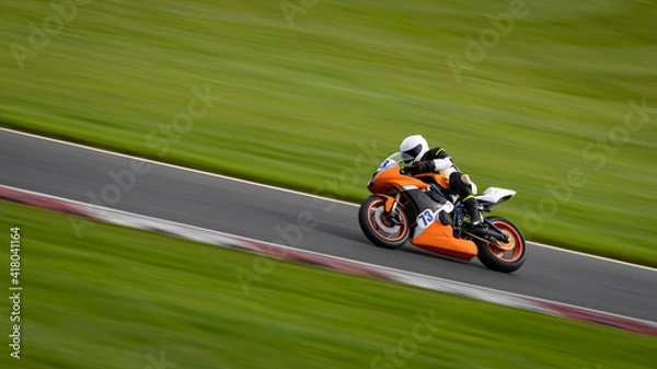 Fototapeta A panning shot of a racing motorbike as it circuits a track.