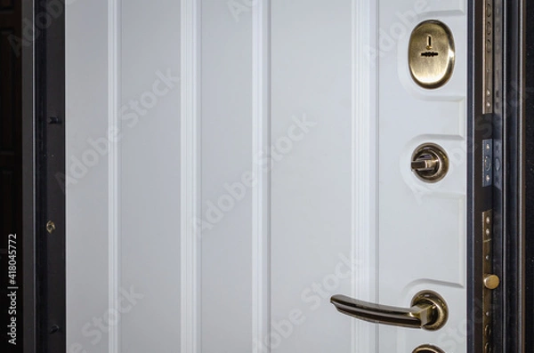 Fototapeta A metal door with a lock, sheathed in white wood.