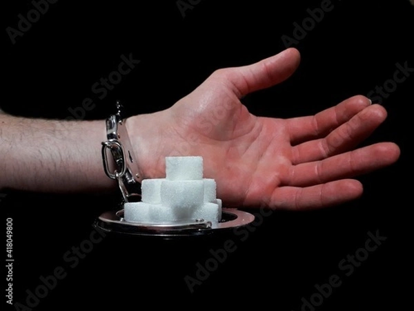 Fototapeta Handcuffed man is addicted to sugar and cocaine, sugar is more addictive than cocaine, white sugar cube and cocaine drug powder pile are linked with handcuffed addicted man hand