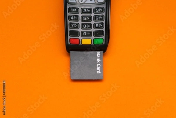 Fototapeta Electronic device for accepting payment cards. Modern POS payment terminal and bank card with copy space. Top view, flat lay