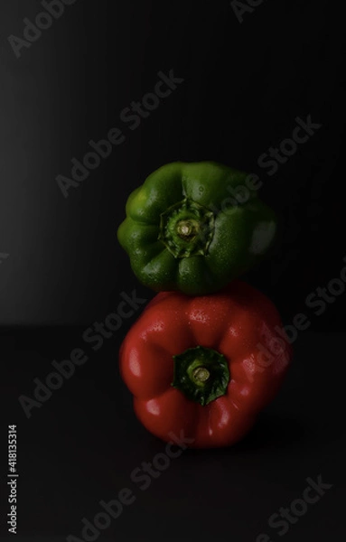 Fototapeta Un poivron rouge au dessus d'un rouge sur fond noir
