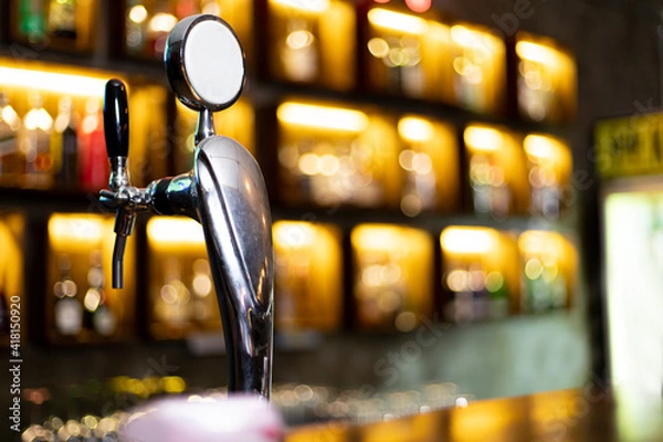 Fototapeta Beer dispenser, Beer dispenser sits on a shelf in front of a vintage bar with a beer or liquor bottle background and beautiful bokeh lights, Alcoholic drinks in a pub for a weekend party.