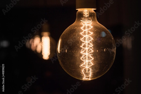 Fototapeta Shining retro light bulb on a dark moody background