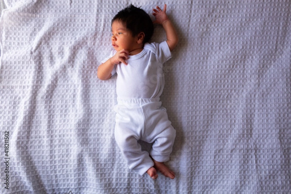 Obraz beautiful newborn hispanic baby on a white sheet, calm and relaxed