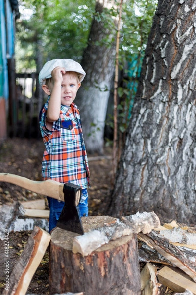 Fototapeta the child cuts wood with an axe and throws it into a pile