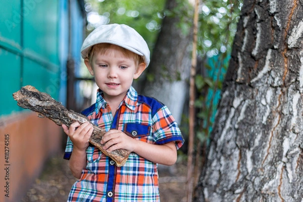 Fototapeta the child cuts wood with an axe and throws it into a pile