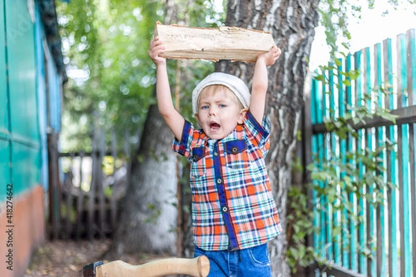 Fototapeta the child cuts wood with an axe and throws it into a pile