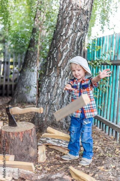 Fototapeta the child cuts wood with an axe and throws it into a pile