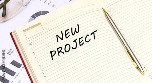 Fototapeta An open diary with text lies on an office desk with financial charts.