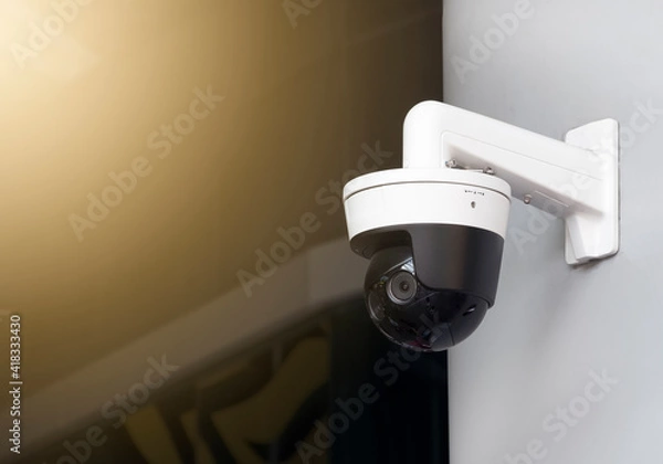 Fototapeta Modern public CCTV camera on the wall with blur building background. Recording cameras for monitoring all day and night. Concept of surveillance and monitoring with copy space.