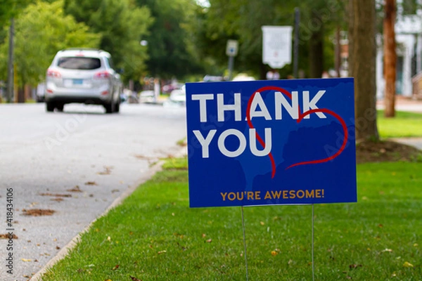 Fototapeta a yard sign by street saying "Thank you, you are awesome" in white and orange text on blue background. A red heart symbol is embedded. Customizable versatile image with copy space for additional text