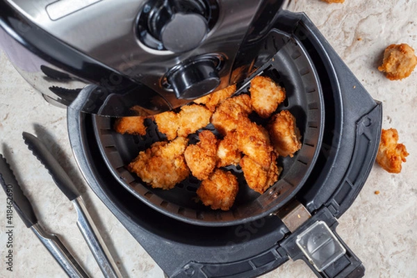 Fototapeta Close up flat lay image of an air fryer oven on kitchen countertop. This offers fast and easy crispy food with little or no fat by circulating hot air inside the basket. A healthy snack alternative.