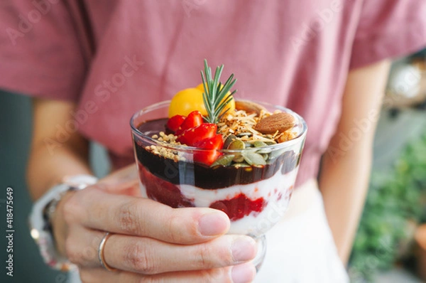 Obraz Selective focus Granola and yogurt with berries in jar on a woman hand. Concept of weight loss, fitness food, healthy eating and balanced diet