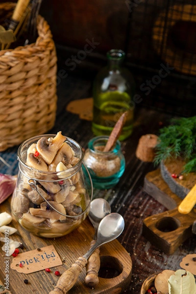 Fototapeta homemade marinated mushrooms in glass jar on wooden board with herbs, dill. pepper, vintage spoons
