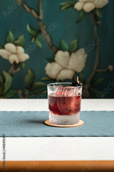Fototapeta red cocktail vodka and cranberry served on the rocks with dried plum on the table at restaurant