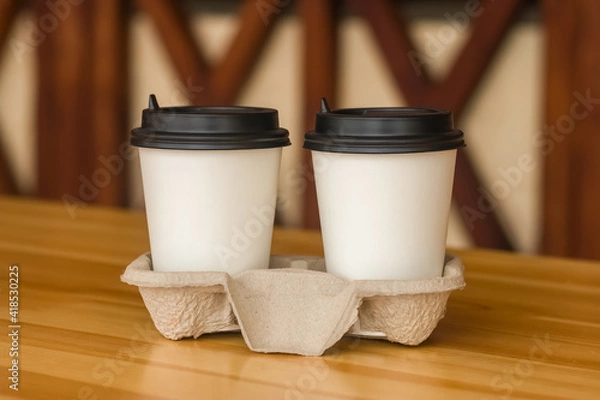 Fototapeta Coffee to go. Two white paper cups with a blank space for the logo.