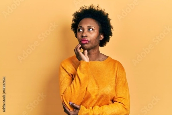 Fototapeta Young african american woman wearing casual clothes with hand on chin thinking about question, pensive expression. smiling with thoughtful face. doubt concept.
