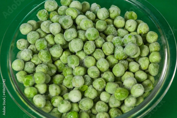 Obraz bowl with frozen peas on green background