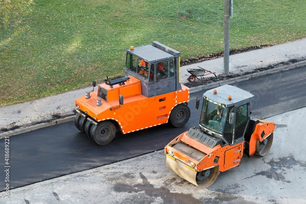 Obraz Two roller compactor machines during operation. Road renewal process. Road construction working, asphalting. High angle view