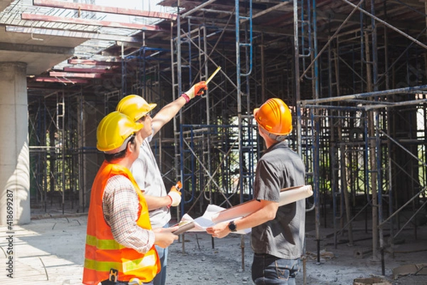Fototapeta Three engineers working in a construction site