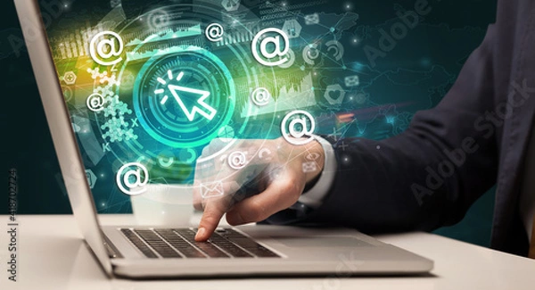 Fototapeta Business hand typing on a modern laptop with cursor icon coming out from multimedia screen, intuitive technology concept